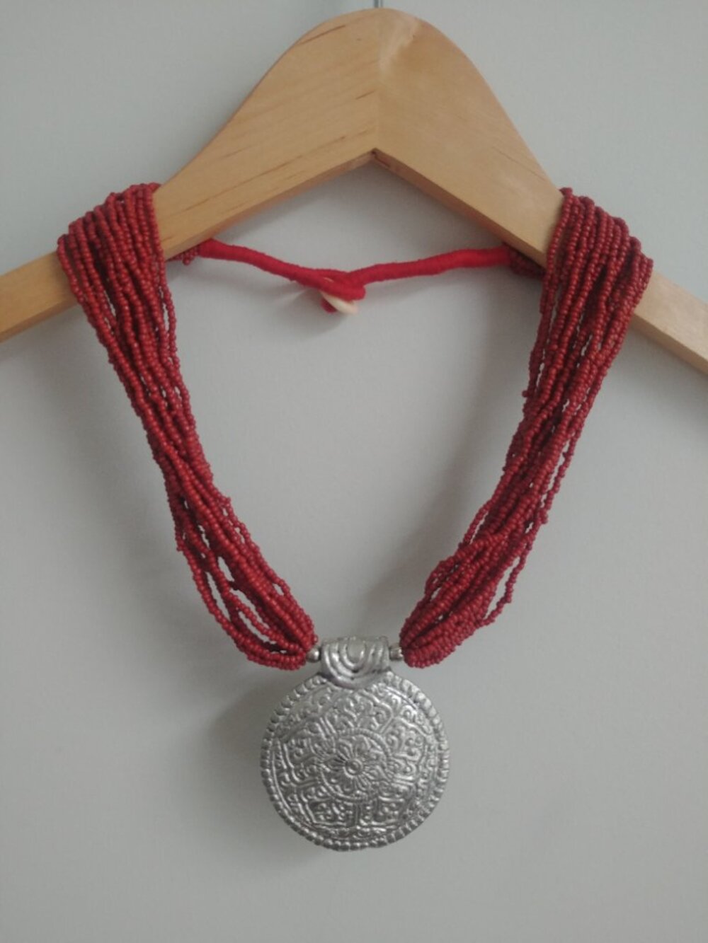 Multi strand beaded burnt orange necklace with large silver medallion pendant